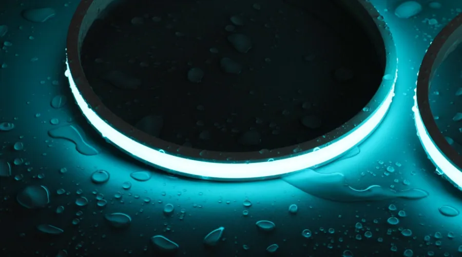 Waterproof LED strip glowing around a round opening on a dark surface covered in water droplets